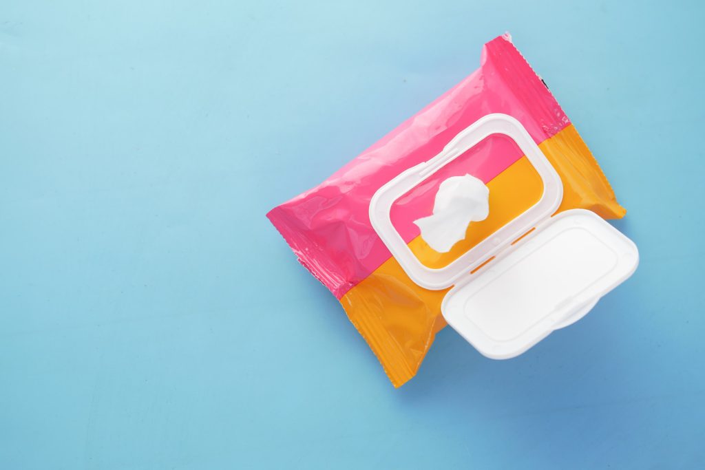 A pink and orange pack of wet wipes on a blue surface